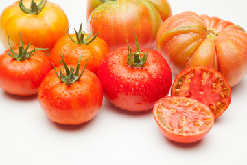 Conjunto de tomates maduros y medio tomate abierto por la mitad.