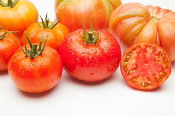 Conjunto de tomates maduros y medio tomate abierto por la mitad.
