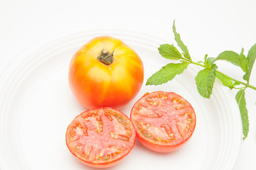 Tomate y hojas de menta sobre fondo blanco