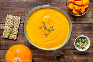 Pumpkin soup with bread rolls on wooden desk, flat lay