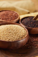 selective focus of white, black and red quinoa in wooden bowls