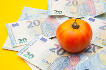 Tomate sobre un nido de billetes, tomate encima de dinero de curso legal. Bonito y saludable tomate...