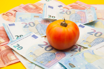 Tomate sobre un nido de billetes, tomate encima de dinero de curso legal. Bonito y saludable tomate...