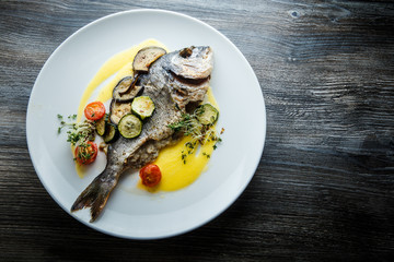 top view on fried fish served with sliced baked vegetables