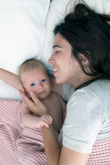 Fototapeta na wymiar Brunette woman playing with baby. Mom hugging baby closeup