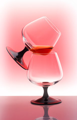 two cognac glasses on red white gradient background
