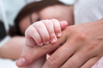 Mom holds the baby by the hand. Brunette woman with baby closeup