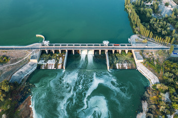 Aerial panoramic view of concrete Dam at reservoir with flowing water, hydroelectricity power...