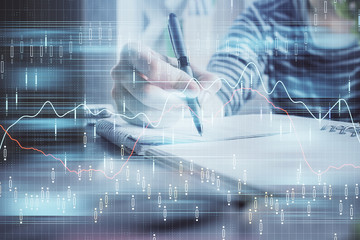 Financial forex graph drawn over hands taking notes background. Concept of research. Double exposure