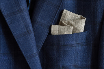Pocket square with embroidery in the breast pocket of a man's blue suit. Wedding accessories