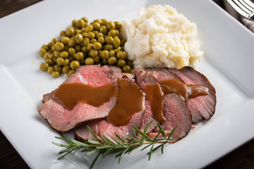 traditional roast beef served with gravy sauce, peas and mashed potato