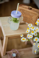 Small woven women bag, a bouquet of daisies, lemonade with mint. Spring. Cozy.