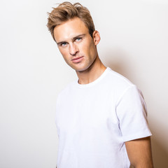 Elegant young handsome man in white T-shirt. Studio portrait.