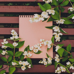 Blank notebook with white flowers on vintage wooden table. Flat lay, copy space.