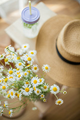 Little wicker women bag, a bouquet of daisies, lemonade with mint, wicker hat, wooden chair. Spring. Cozy.