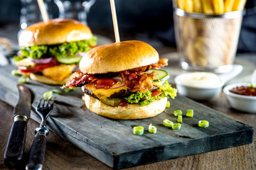 close-up view of tasty burgers, glasses of beer and french fries on table 