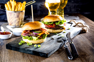 close-up view of tasty burgers, glasses of beer and french fries on table 