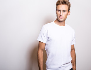 Elegant young handsome man in white T-shirt. Studio portrait.