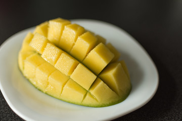 Cut mango to cubs on plate closeup. Slices of organic mango fruit.