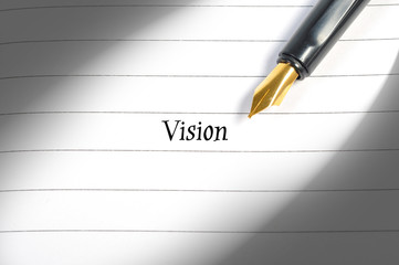 Fountain pen on notebook with word Vision