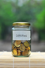 Coins in bottle with label Utilities - financial concept