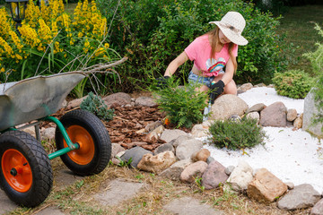 Child cultivating alpine rock garden helping parents