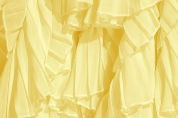 Soft pastel color chiffon fabric folds. Yellow dress with ruffles and frills. 