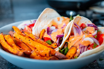 Healthy pitta kebabs and sweet potato fries with onions, peppers, coriander and spring onions in a large bowl