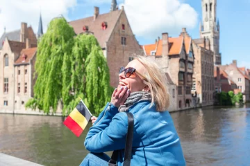 Tableau sur plexiglas Bruges A young woman with the flag of Belgium in her hands is enjoying the view of the canals in the historical center of Bruges.  © LALSSTOCK