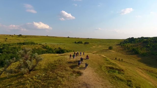 Meadows with hills and forest with a bird's eye view.. Drone flies over the beautiful places of Ukrain On the hill are bikers.e.
