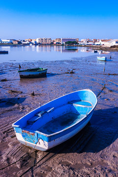 FISHING BOAT MOORED IN THE PORT WITH LOW TIDE AND HORIZON OF BLUE SKY AND PEOPLE OF ANDALUSIA IN SPAIN