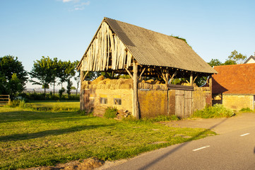 Fototapeta na wymiar Dilapidated hay barn in the light of the setting sun