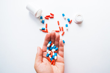 Multicolored capsules in hand isolated on white background, copyspace for text, selective focus, top view. Pain meds, health, pills for the treatment of the concept of drug abuse