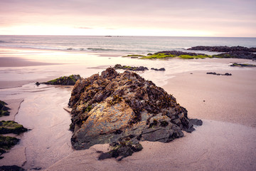 ROCK ON THE SHORE OF THE BEACH WITH TIDE LOW IN THE EVENING IN THE NORTH OF SPAIN