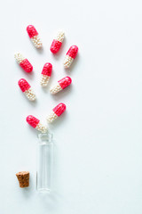 Pink bottle capsules on white isolated background, copyspace for text, selective focus, top view. Pain drugs, health, pills for the treatment of the concept of addiction