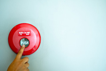 finger is pushing a fire alarm button equipment  on the wall