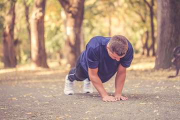 Young athletic man doing push ups in the park