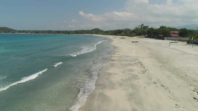 Beautiful tropical beach Cabugao with white sand and palm trees in the Philippines, Luzon. Aerial view of coast with beach and turquoise water.