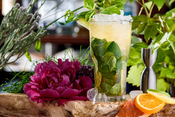 mojito with ice and slices of lime in beautiful glass on the background of fresh flowers