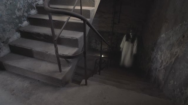 A ghost of a woman with a rusty cage on his head and with shackles on his hands wanders the stairs of an old abandoned building.