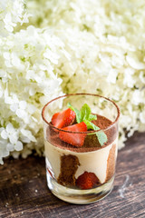 Traditional Italian dessert Tiramisu, decorated with fresh strawberries in a transparent glass