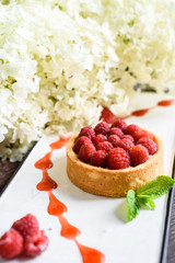 Obraz na płótnie Canvas raspberry tart on a white plate on a dark wooden background