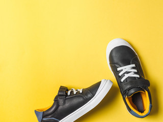 pair of new kids or adult sneakers on yellow background, top view. Flat lay gray and yellow or...