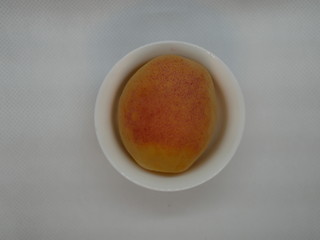 one ripe apricot in a small white porcelain plate on a white background. Natural vitamin. Healthy food. vegetarian food.