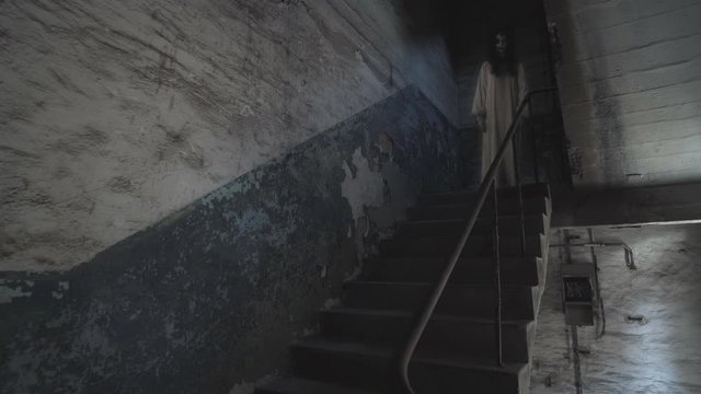 A ghost of a woman with a rusty cage on his head and with shackles on his hands wanders the stairs of an old abandoned building.
