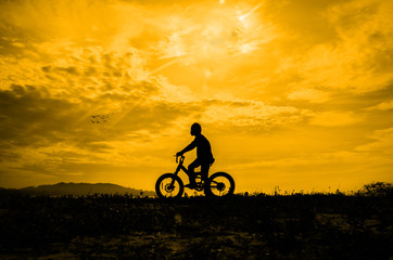 Silhouette of a boy riding a bicycle