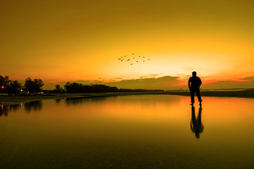 Silhouette of a men looking to the beautiful sky during golden sunset
