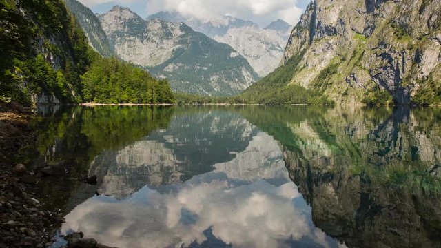 Timelapse of clouds moving over Obersee lake, reflecting mountains in Bavaria, Germany