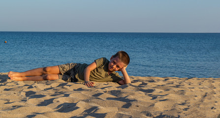 Sports child does yoga and meditates on the beach. The sandy beach is quiet and peaceful. Copy...