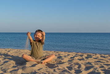 Sports child does yoga and meditates on the beach. The sandy beach is quiet and peaceful. Copy...